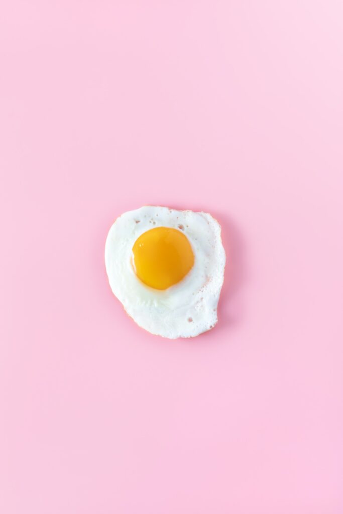  A sunny-side up egg on a pale pink background.
