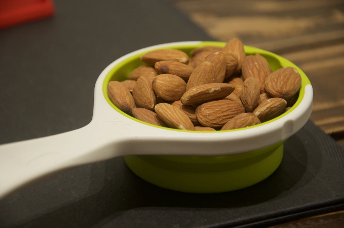 a ¼ cup measuring cup full of almonds.