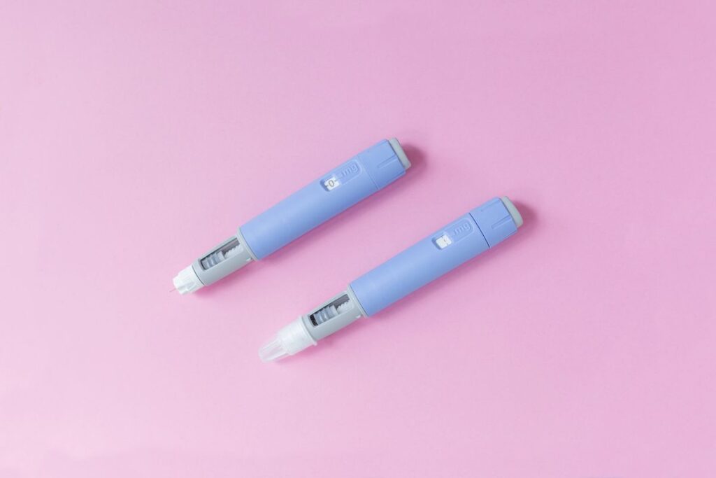 two injection medication pens with a pink background 