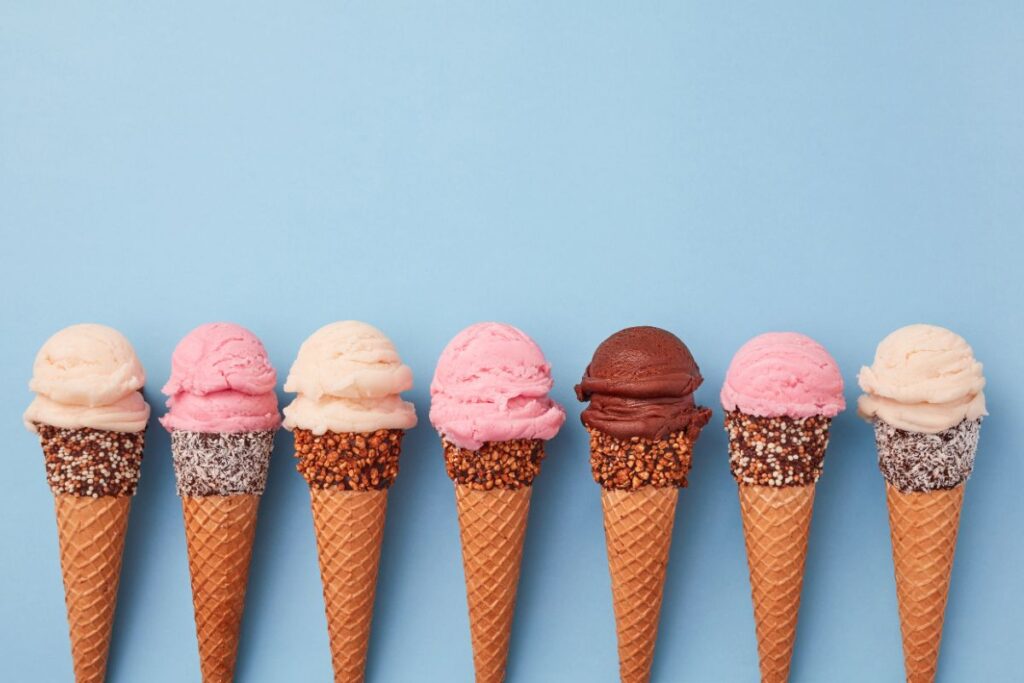 Multiple ice cream cones lined up with a blue background 