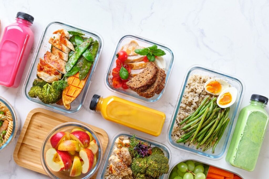 five glass meal prep containers for balanced gastric sleeve meals including eggs, shrimp, rice, green Eans and broccoli with three different smoothies in clear bottles.